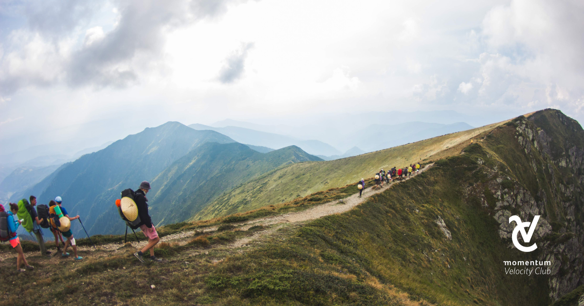 A group of hikers walking on a hiking trail through the mountains.