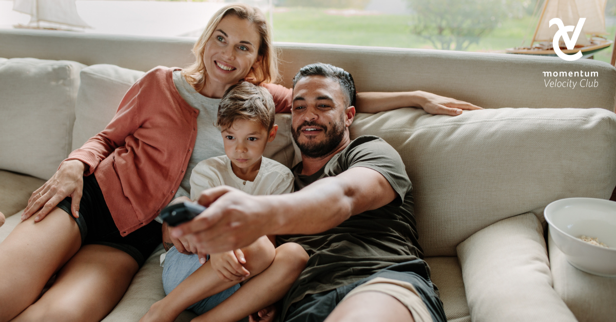 Mom and dad relaxing on the couch with their young child watching TV.