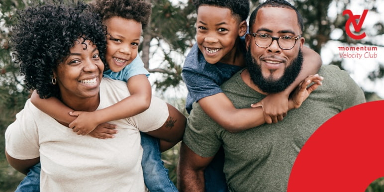 Mom and dad holding their children on their backs. They are enjoying themselves outdoors.