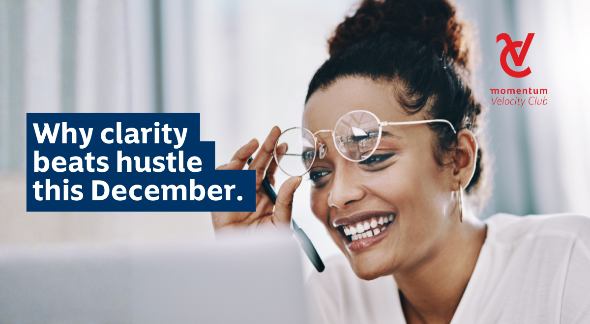 A smiling young woman putting on her reading glasses so she can clearly read from her laptop screen.