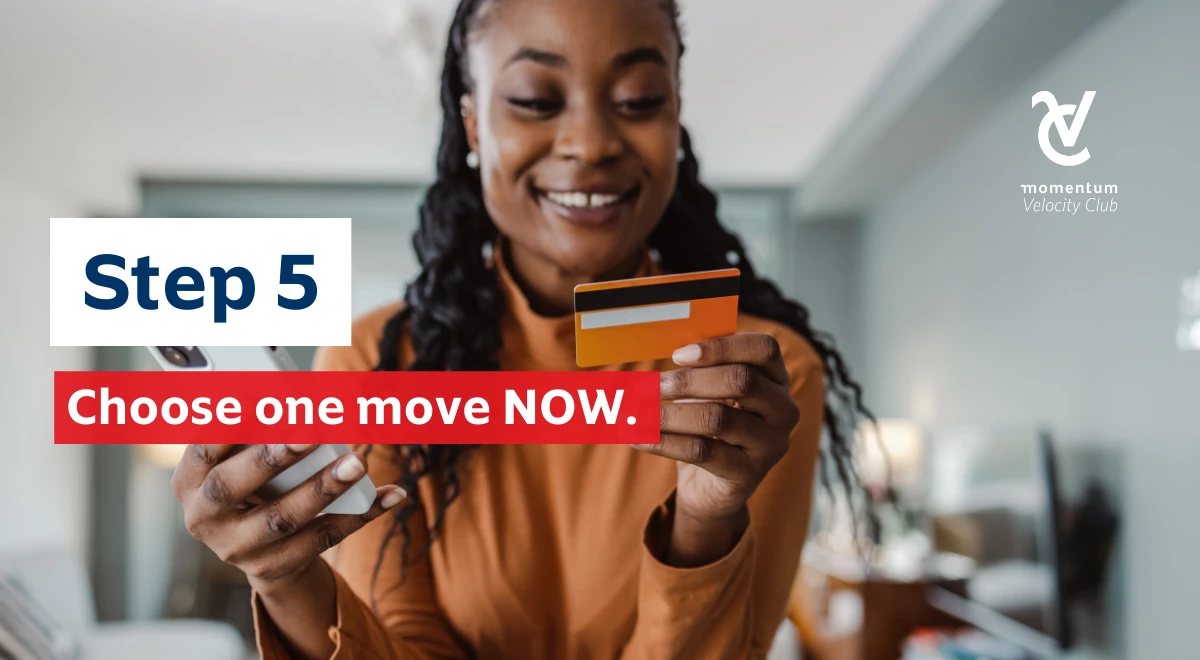 A woman looking at her credit card with a cell phone in hand, smiling with confidence because she&rsquo;s made a good financial decision that will set her up for success in 2026.